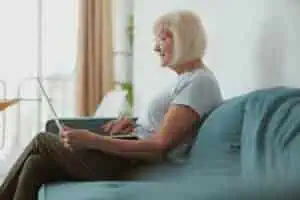 Modern old lady using laptop computer at home