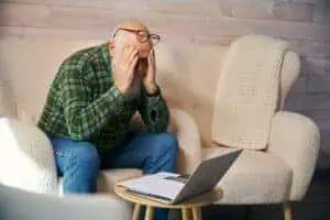 Old man is tired, working with documents in living room