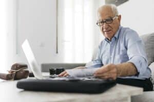 Senior man working with a computer and his old photo cameras and old photos