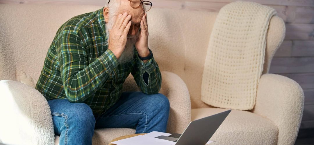 Old man is tired, working with documents in living room